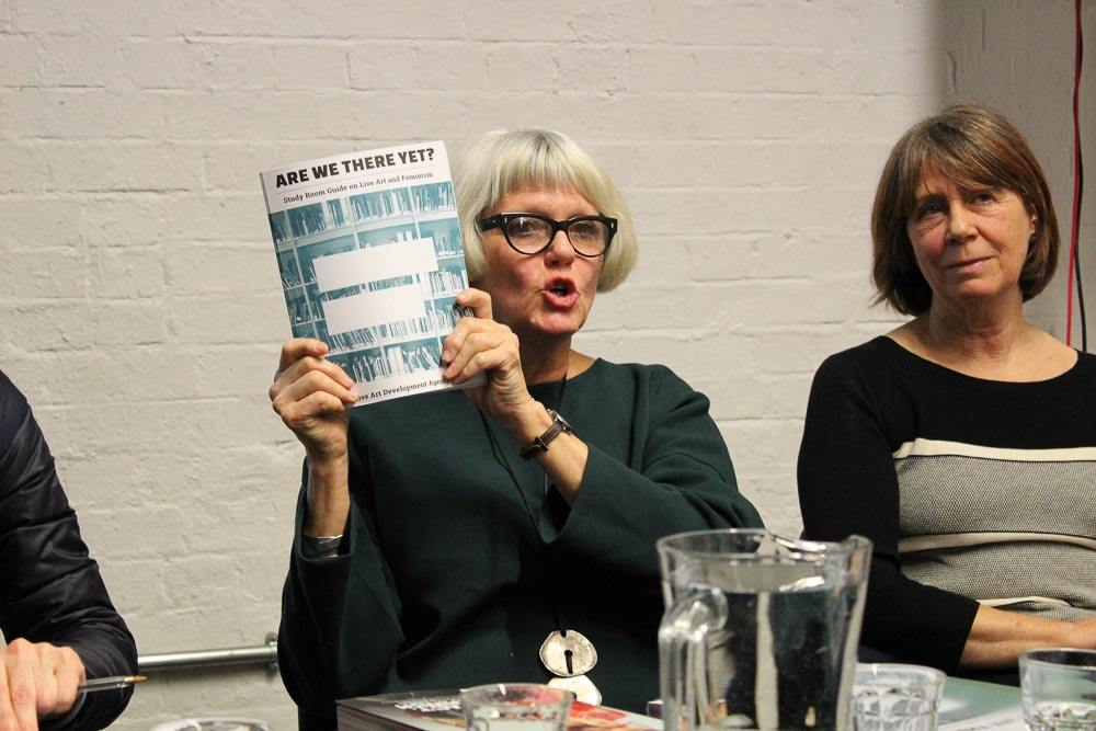 Lois Weaver holding up a Study Room Guide and Claire McDonald sitting beside her