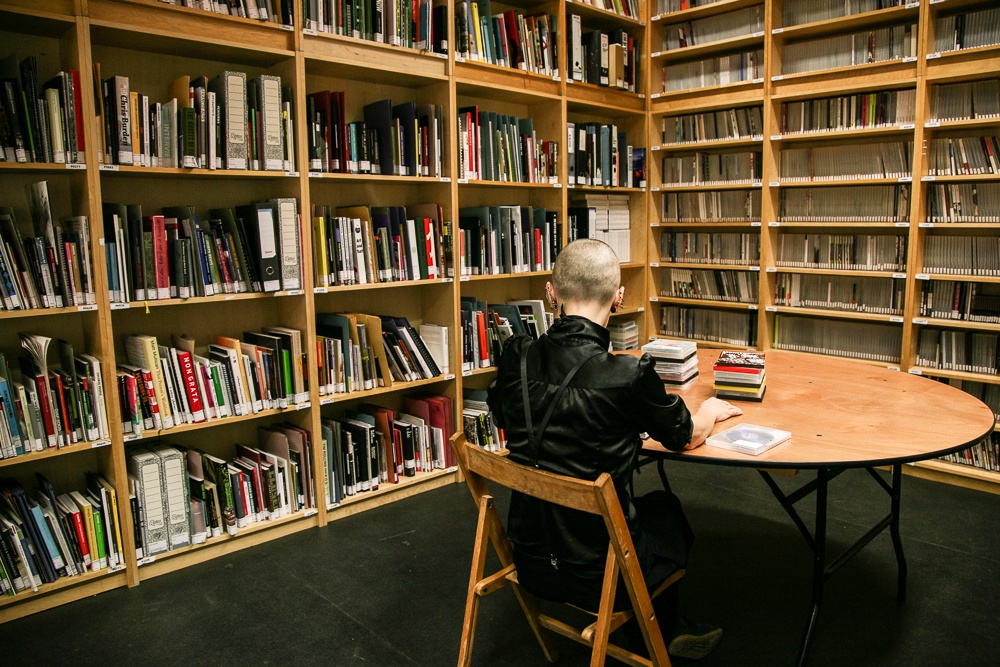 person sitting at a table in front of full bookshelves in the study room