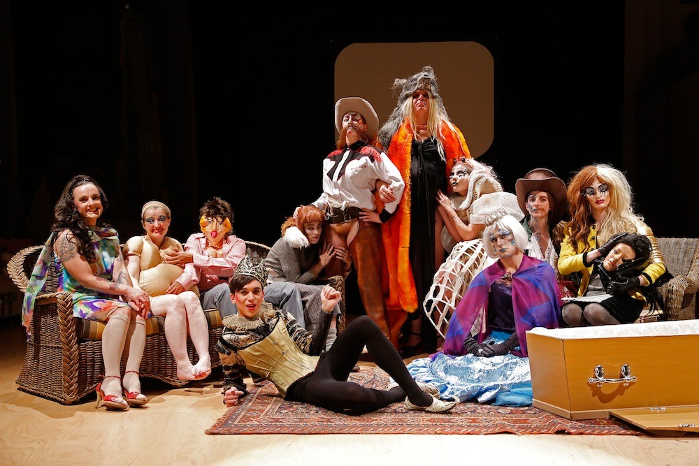 Group of people dressed in drag sitting, standing and lying on the floor