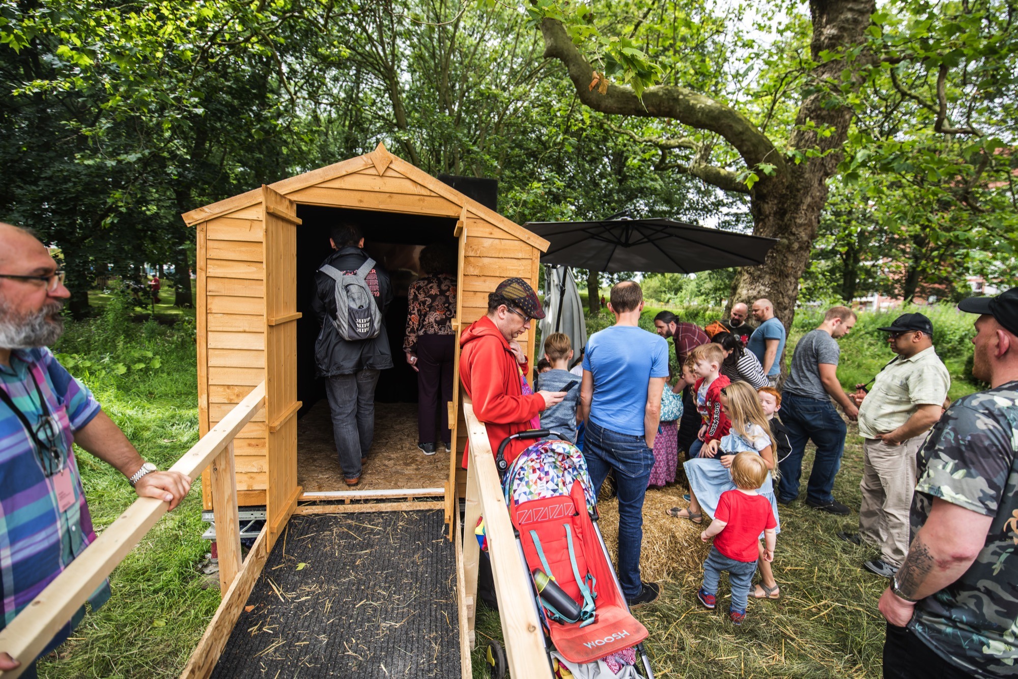 people waiting outside a wooden shed