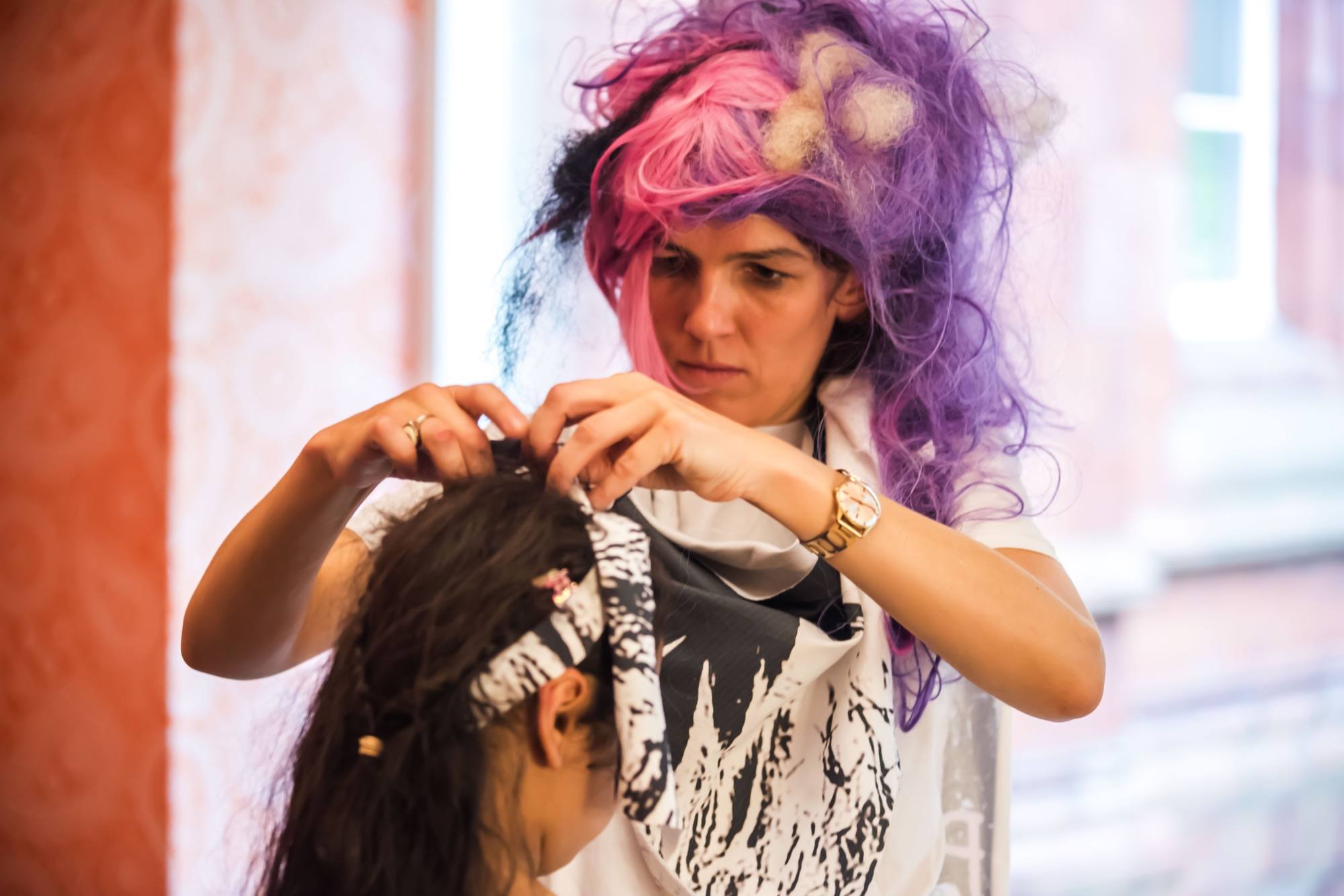 person having their hair done by a woman with crazy pink hair