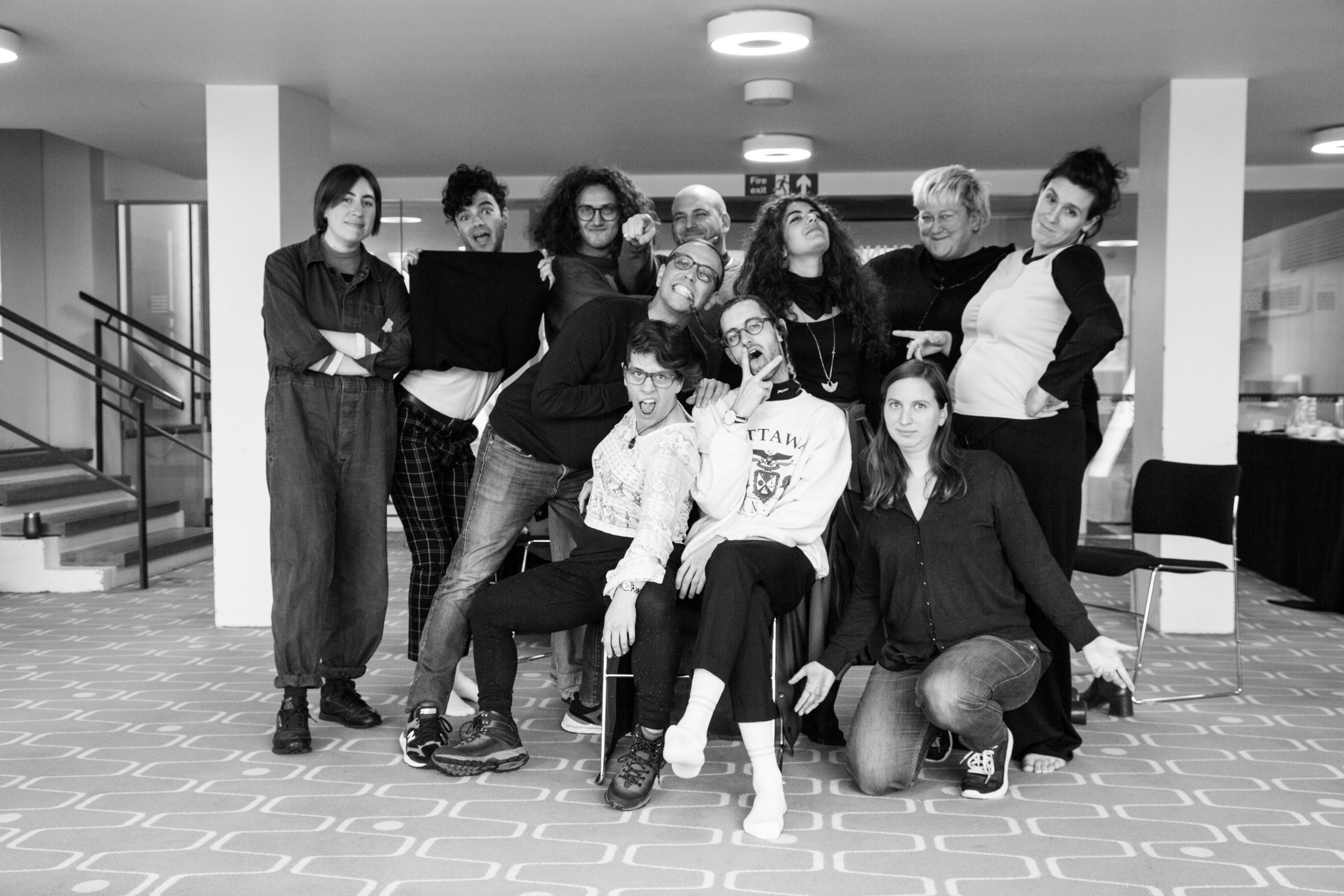 a black and white image of 11 people stood together smiling for the camera