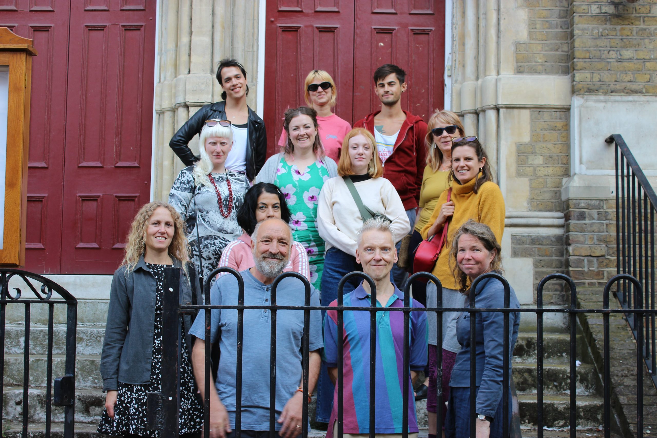 13 people stand on the steps in from of LADA's building smiling for the camera