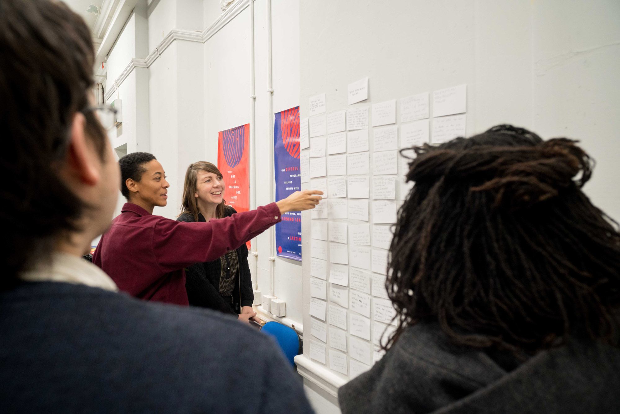 A group of participants look at notes on a wall.