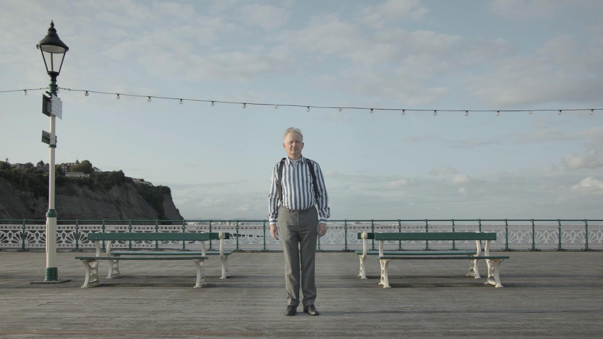 Tim Bromage is stood on a pier.