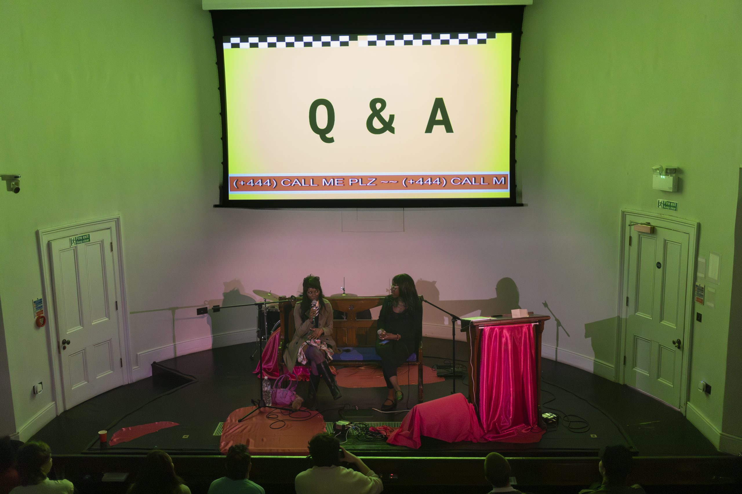 Two black people sit on a church pew with a projection saying Q&A behind.