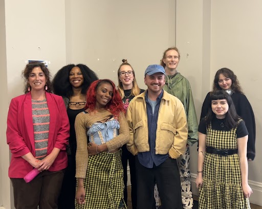 A group of people stand facing the camera smiling.